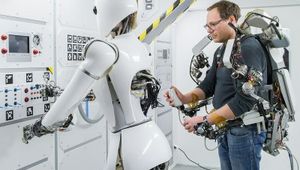 Ein Operator steuert den humanoiden Roboter AILA mihilfe eines aktiven Oberkörper-Exoskeletts